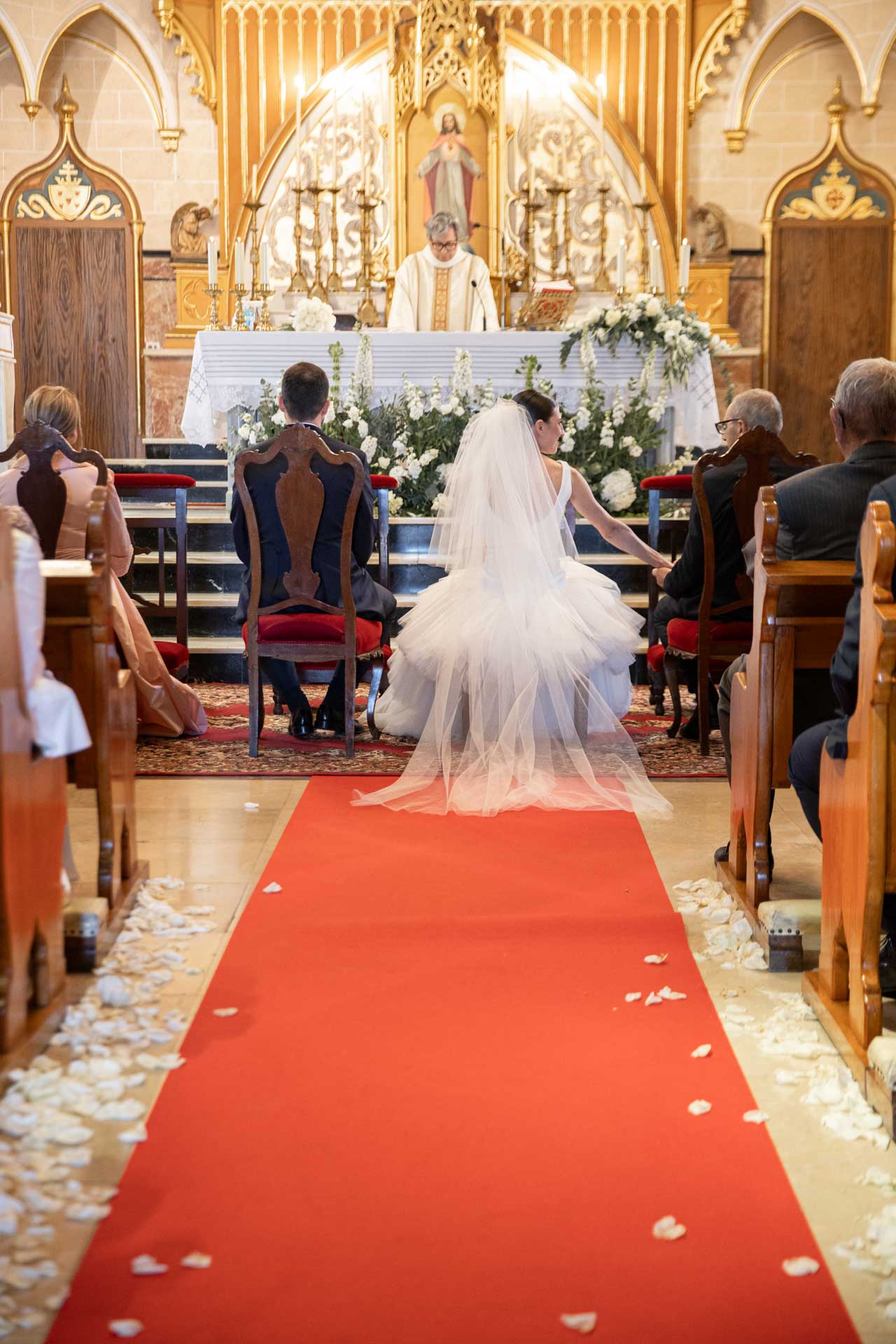 Imagen de los novios de espaldas junto al altar en la ceremonia religiosa de su boda