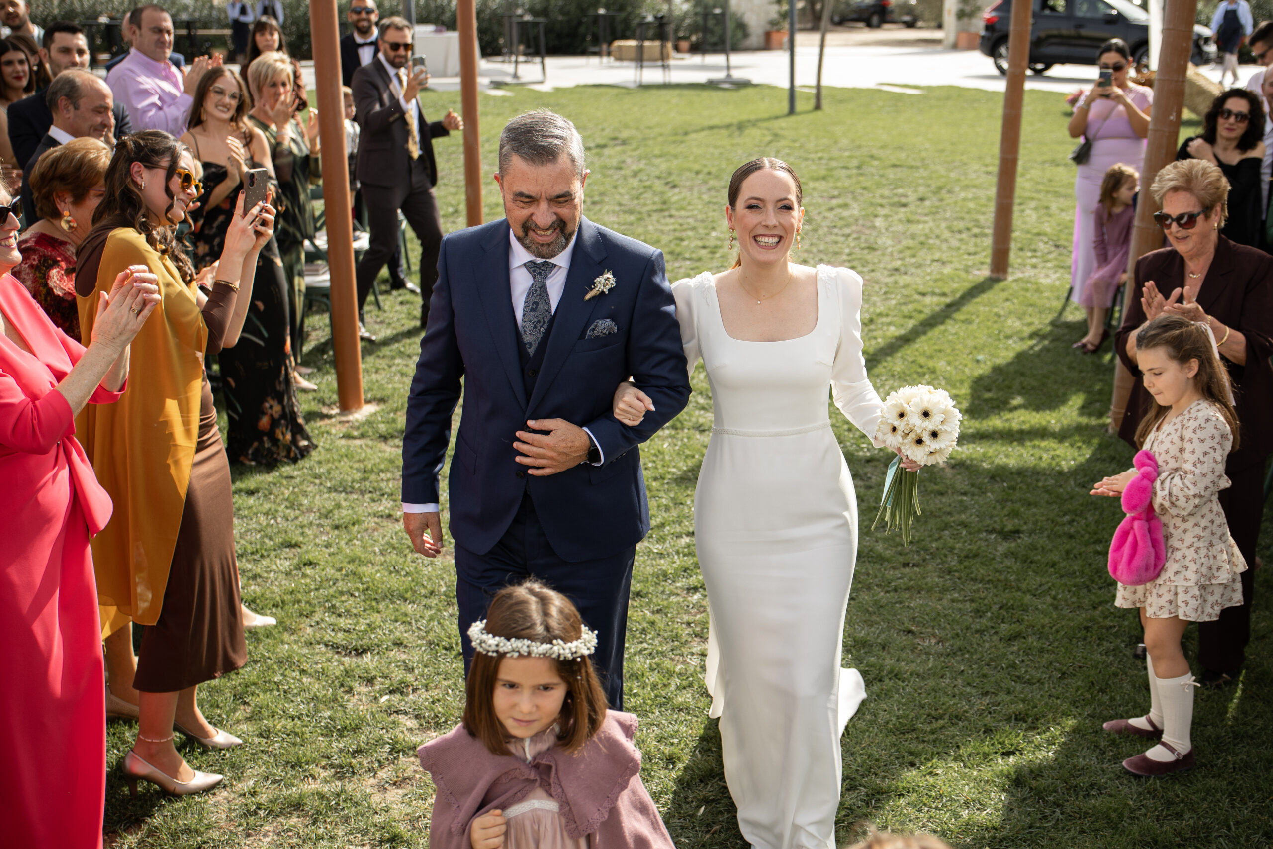 Novia entrando con el padrino a la ceremonia emocionada el día de su boda en la finca El Caserío en Muro de Alcoy