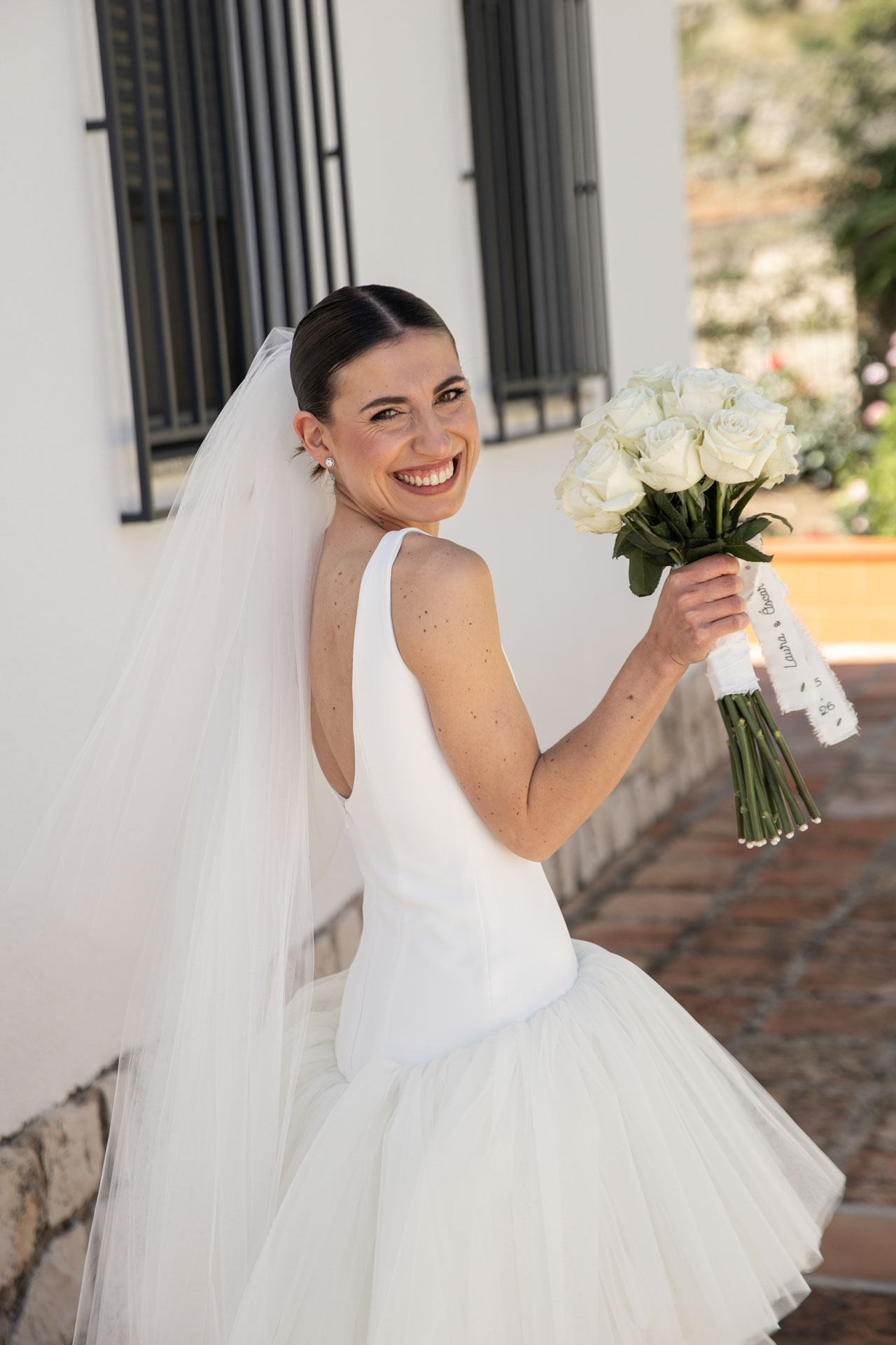 Retrato de novia el día de su boda con el ramo mirando a cámara