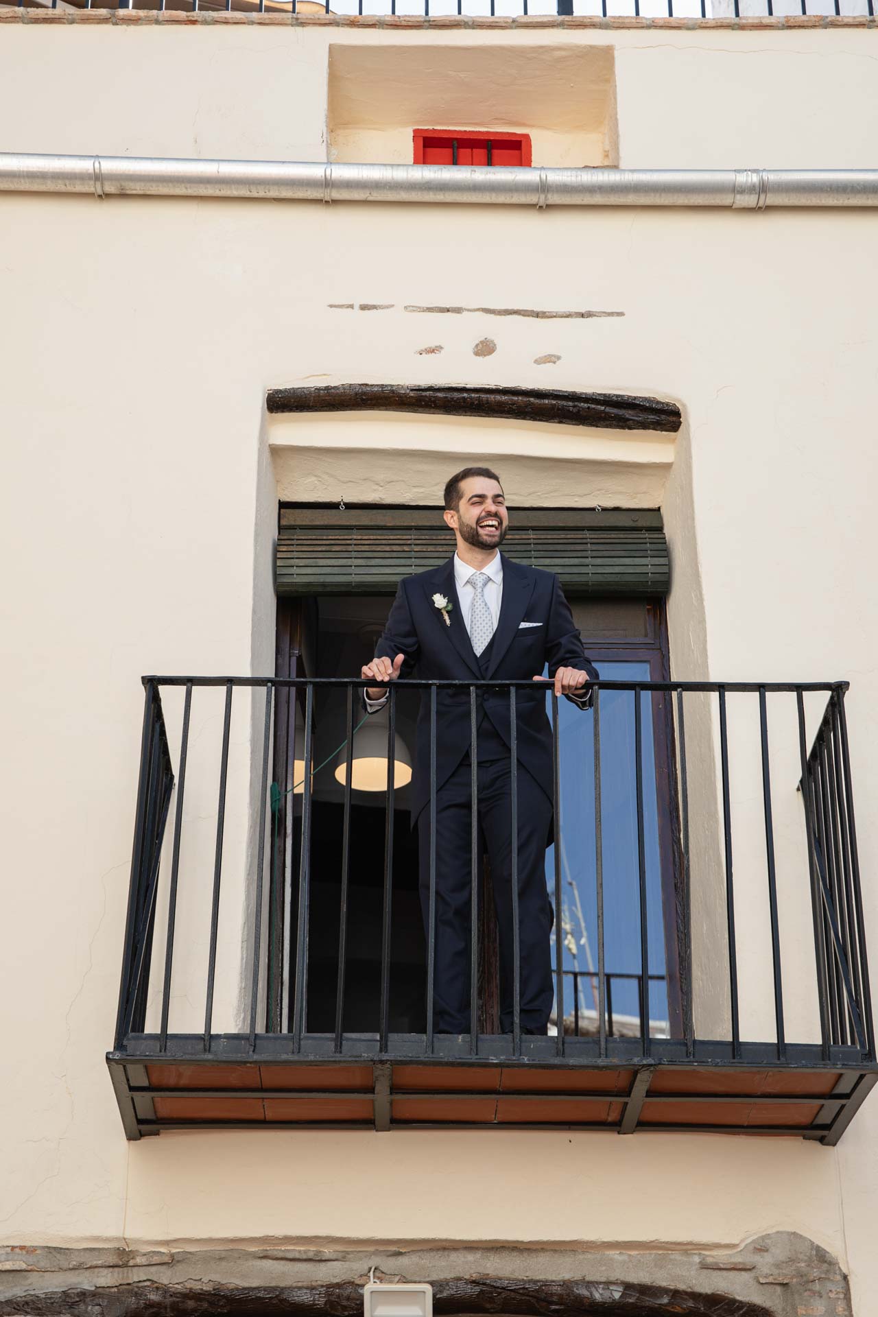 Novio asomado al balcón de su casa el día de su boda